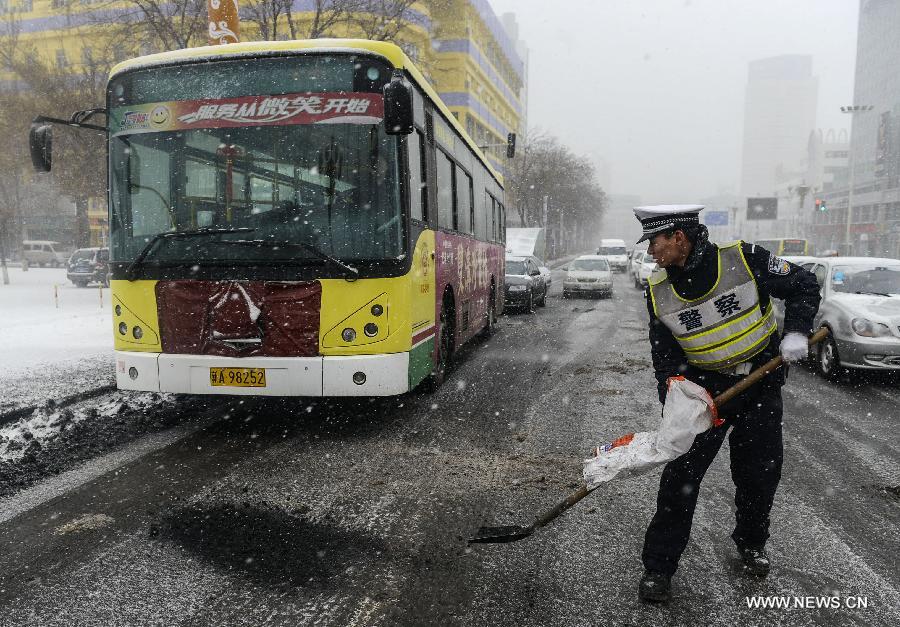 A traffic policeman cleans a street amid a spring snow in Urumqi, capital of northwest China's Xinjiang Uygur Autonomous Region, March 8, 2013. (Xinhua/Wang Fei)