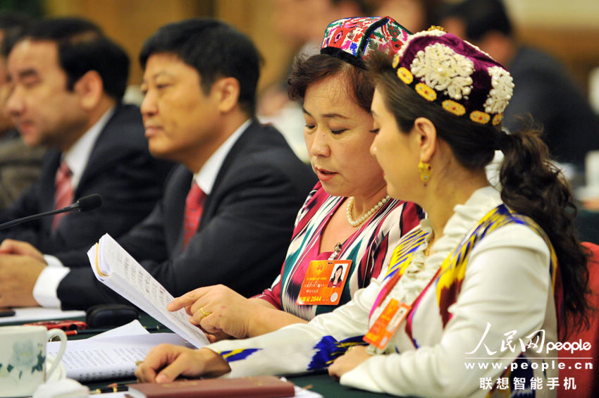 Two female ethnic minority deputies wear traditional ethnic minority costume takes part in a discussion of the first session of Xinjiang delegation to 1st session of 12th NPC at the Great Hall of the People in Beijing, capital of China, March 5, 2013. (People's Daily Online/Weng Qiyu)