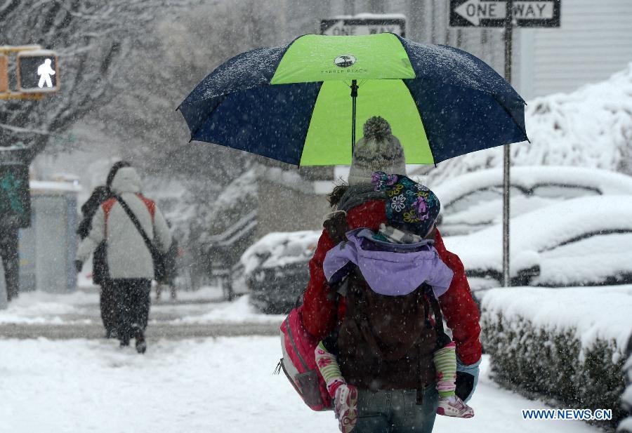 A parent carries her child on her back to school amid snow at Queens borough in New York, the United States, March 8, 2013. A late winter snowstorm hit New York on Wednesday. (Xinhua/Wang Lei) 