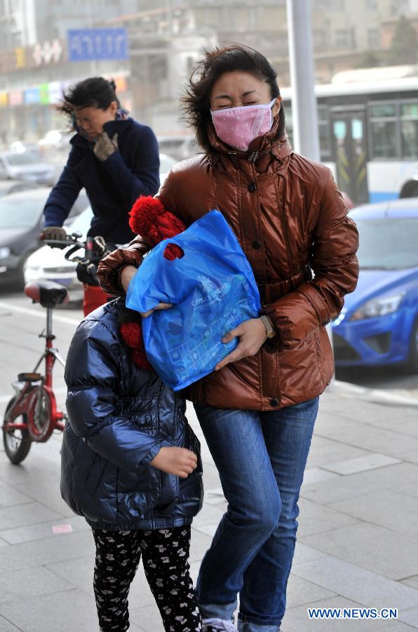 Pedestrians walk in strong wind in Beijing, capital of China, March 9, 2013. A cold front brings strong wind as well as sand and dust to Beijing on March 9. (Xinhua/Li Wen)