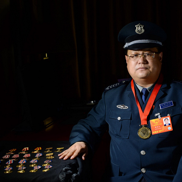 Zhu Liangyu, a deputy of the NPC, poses with his various badges of honor on March 6, 2013. Zhu, an assistant manager in the Haidian district branch of the Beijing General Security Company wants peasant-workers and migrant workers to receive fair treatment as citizens in terms of housing, medical treatment and pensions. [Photo/Xinhua]