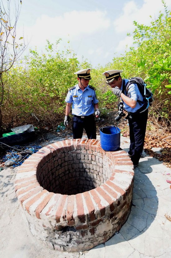 Marine surveillance officers investigate an ancient well and the water in it on the Ganquan Island, an uninhabited island of the Xisha Islands in the South China Sea, March 11, 2013. Crew members aboard the Chinese marine surveillance ship Haijian 262 patrolled the Ganquan Island on Monday. (Xinhua/Wei Hua) 