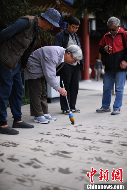 Zhao, 68, worked in the Ministry of Posts and Telecommunications before retirement. He loves calligraphy, especially the ground calligraphy after retirement. He has left his handwritings on the ground of Beihai, Jiangshan and Tiantan Park. "The ground calligraphy can practice brawn and also the brain. My handwritings on the ground will attract the elderly with the same hobby. Talking with them brings me a lot fun."(Chinanews/Lin Peiqing)