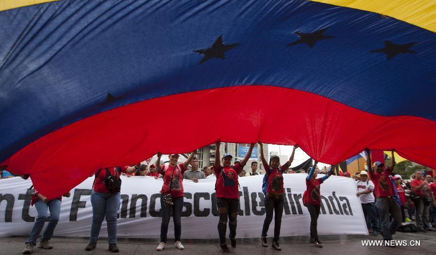 Supporters flutter a giant national flag during a rally held after Venezuela's Acting President Nicolas Maduro's official registration as candidate for presidential elections of April 14, outside the headquarters of the National Electoral Council of Venezuela in Caracas, capital of Venezuela, on March 11, 2013. (Xinhua/Juan Carlos Hernandez) 