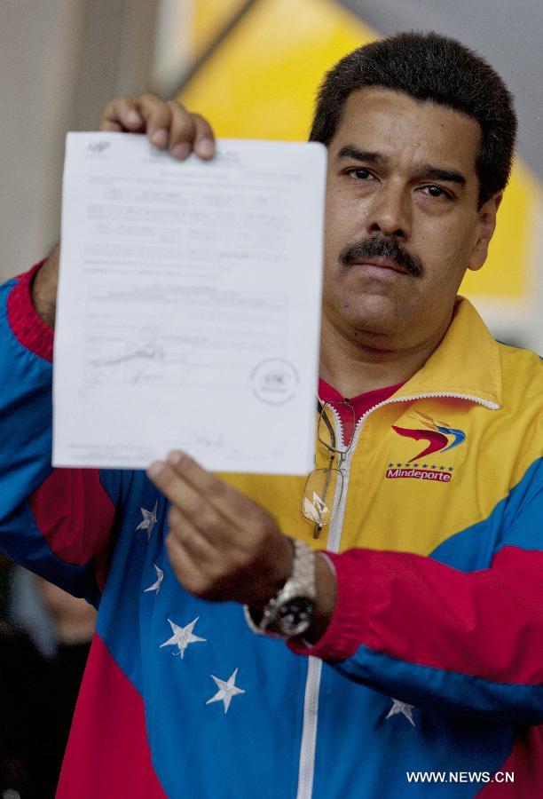 Venezuela's acting President Nicolas Maduro shows his official registration as candidate for presidential elections of April 14, outside the headquarters of the National Electoral Council of Venezuela in Caracas, capital of Venezuela, on March 11, 2013. (Xinhua/Guillermo Arias) 