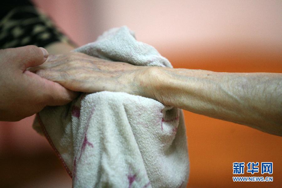 Nurse gives a 80 year-old woman a hand massage in a nursing home in Nanjing on Oct 1, 2012.(photo/Wang Xin)