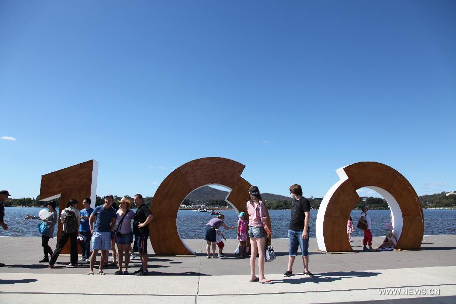 People pose for a souvenir photo near Griffin Lake in Canberra, Australia, March 11, 2013. Canberra marked its 100th anniversary on Tuesday. (Xinhua/Qian Jun)