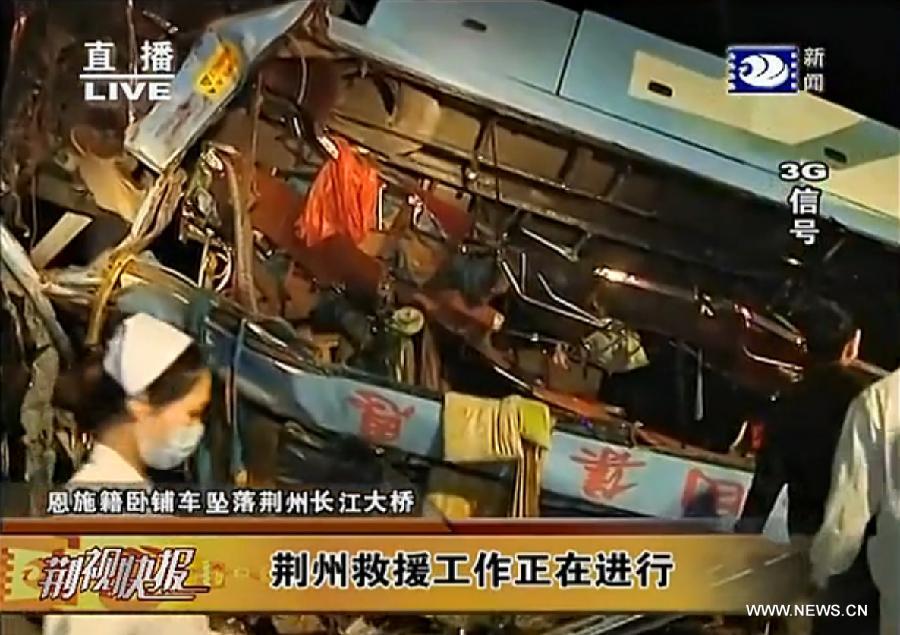 This video grab captured on March 12, 2013 shows a sleeper coach which fell off the Jingzhou Yangtze River Bridge in Jingzhou, central China's Hubei Province. The accident happened at around 7:00 p.m. Tueday when the sleeper coach fell off a road bridge after a tyre burst. More than 20 passengers, most of whom are migrant workers, are still trapped in the coach as rescuers are deployed to the accident scene. (Xinhua) 