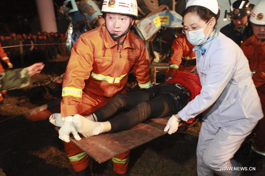 Rescuers carry a victim of a traffic accident as a sleeper coach fell off the Jingzhou Yangtze River Bridge in Jingzhou, central China's Hubei Province, March 12, 2013. At least 14 people were killed and nine injured during the the accident which happened at around 7:00 p.m. Tuesday when a flat tire caused the coach to break through the guardrail at the southern end of the bridge and hit the ground underneath the structure. Rescue work is under way. (Xinhua/Shi Jiuyong) 