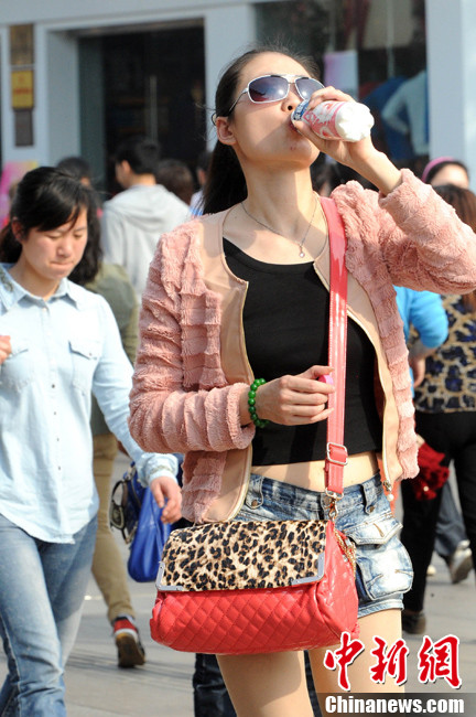 A pedestrian wearing spring clothes walks on the street in Jiangsu on March 9, 2013. (Photo/CNS)