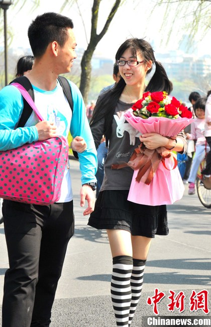 Pedestrians wearing spring clothes walk on the street in Hangzhou on March 9, 2013. (Photo/CNS) 
