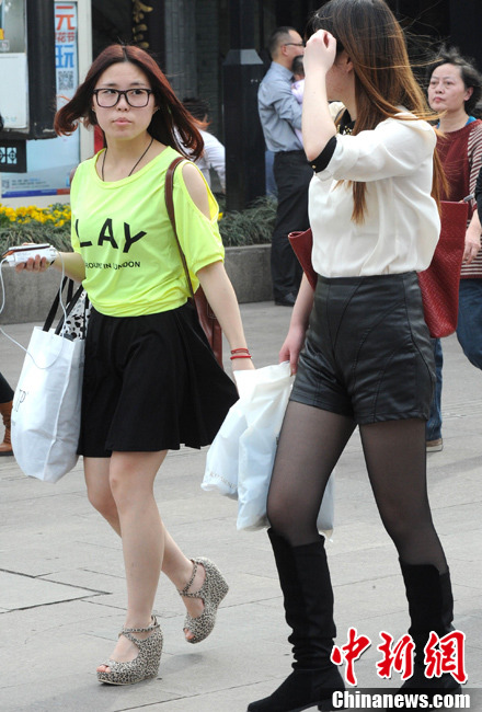 Pedestrians wearing spring clothes walk on the street in Jiangsu on March 9, 2013(Photo/CNS)