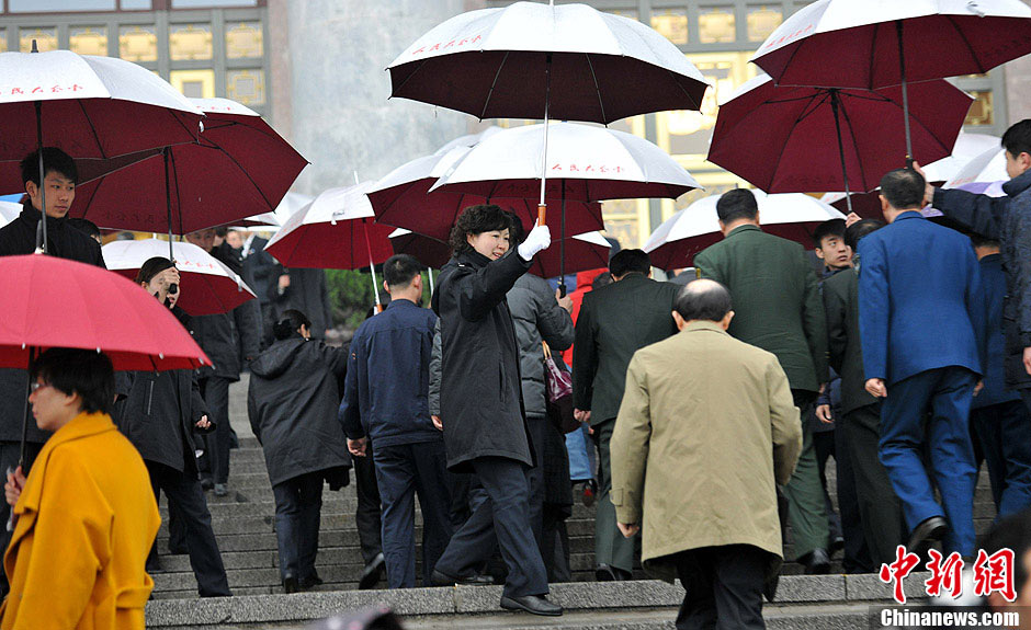 The photo shows delegates with umbrellas entering the Great Hall of the People. (CNS/Jin Shuo)