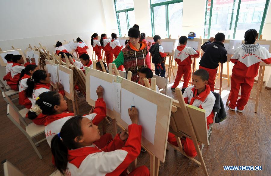 A teacher (C) of the Tibetan ethnic group gives an art class at No. 1 Primary School of Deqin County in Diqing Tibetan Autonomous Prefecture, southwest China's Yunnan Province, March 12, 2013. A total of 1,260 pupils, most of whom are of the Tibetan ethnic group, study at this school, which was founded in September 2012. Pupils here are offered free meals and lodging. (Xinhua/Lin Yiguang) 