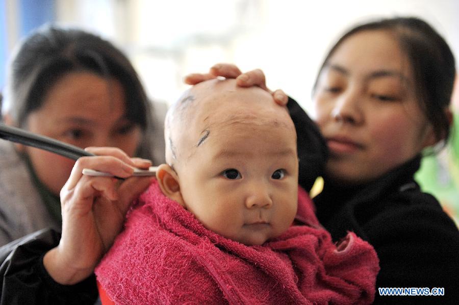A baby has haircut at a barbershop in Baokang County, central China's Hubei Province, March 13, 2013, on the occasion of the second day of the second lunar month, known in Chinese as Er Yue Er, "a time for the dragon to raise its head", as a Chinese saying goes. Barbershops across the country opened early to begin one of their busiest days of the year, as many Chinese hold the superstitious belief that getting a haircut at a time when the "dragon raises its head" means they will have a vigorous start to the new year. (Xinhua/Yang Tao)