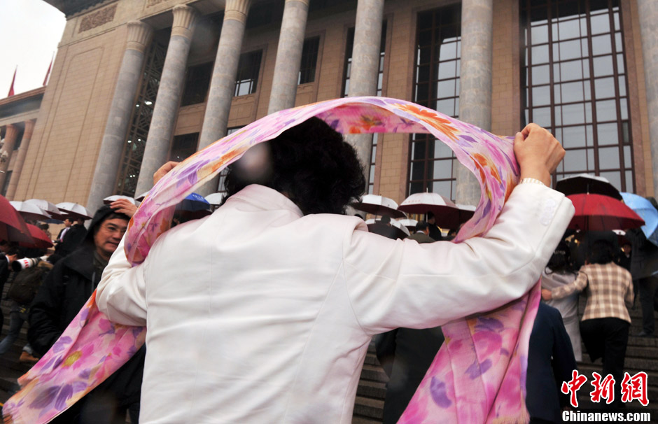 Photo shows a female member of the 12th National Committee of the Chinese People’s Political Consultative Conference (CPPCC) walking up the stairs to the Great Hall of the People with a scarf covering her head in the rain. (Chinanews.com/ Jia Guorong)