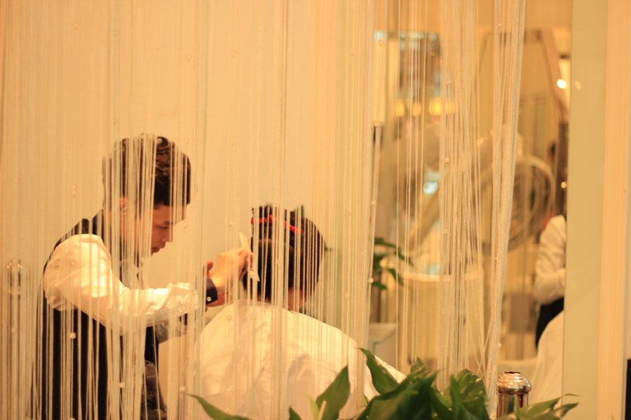 A barber cuts a customer's hair in a barber shop at Wanda Plaza in Beijing on Wednesday, March 13, 2013. (CRIENGLISH.com/Liu Yuanhui)
