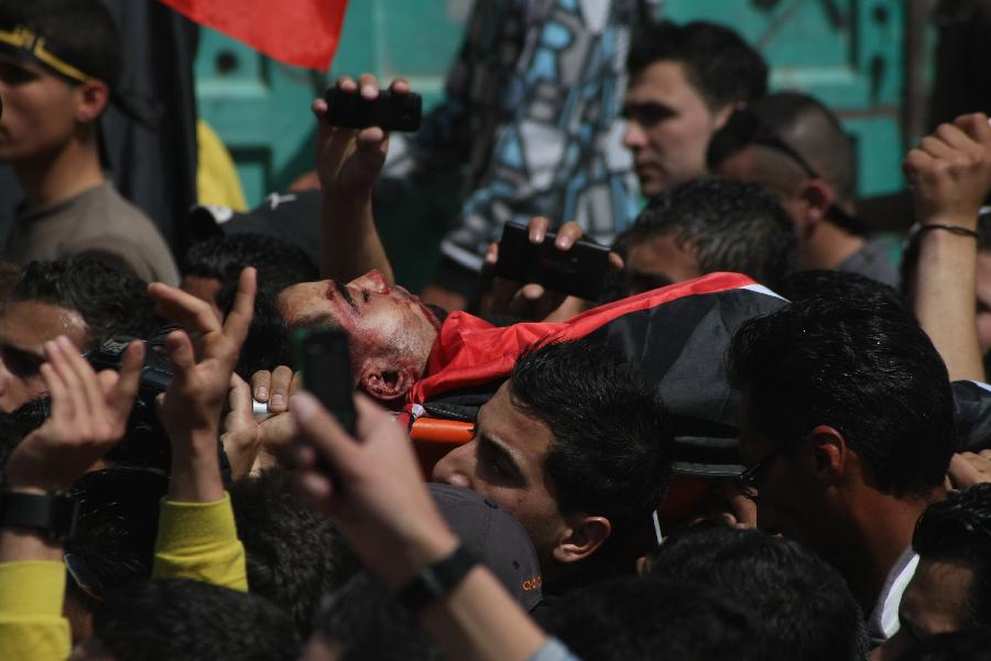 Palestinians carry the body of Mahmoud Al-Titi during his funeral in the West Bank city of Hebron, on March 13, 2013. Israeli forces shot dead a Palestinian and wounded two during clashes in the West Bank city of Hebron, medical sources and witnesses said Tuesday. (Xinhua/Mamoun Wazwaz) 