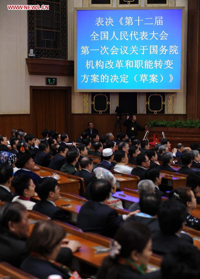 Deputies vote on a draft resolution on the plan of institutional reform and functional transformation of the State Council during the fourth plenary meeting of the first session of the 12th National People's Congress (NPC) at the Great Hall of the People in Beijing, capital of China, March 14, 2013. Chairman, vice-chairpersons, secretary-general and members of the 12th NPC Standing Committee, president and vice-president of the state, and chairman of the Central Military Commission of the People's Republic of China will also be elected here on Thursday. (Xinhua/Li Tao)