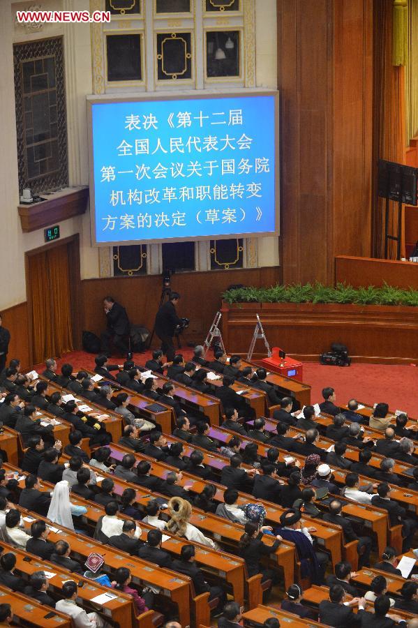 Deputies vote on a draft resolution on the plan of institutional reform and functional transformation of the State Council during the fourth plenary meeting of the first session of the 12th National People's Congress (NPC) at the Great Hall of the People in Beijing, capital of China, March 14, 2013. Chairman, vice-chairpersons, secretary-general and members of the 12th NPC Standing Committee, president and vice-president of the state, and chairman of the Central Military Commission of the People's Republic of China will also be elected here on Thursday. (Xinhua/Wang Song)