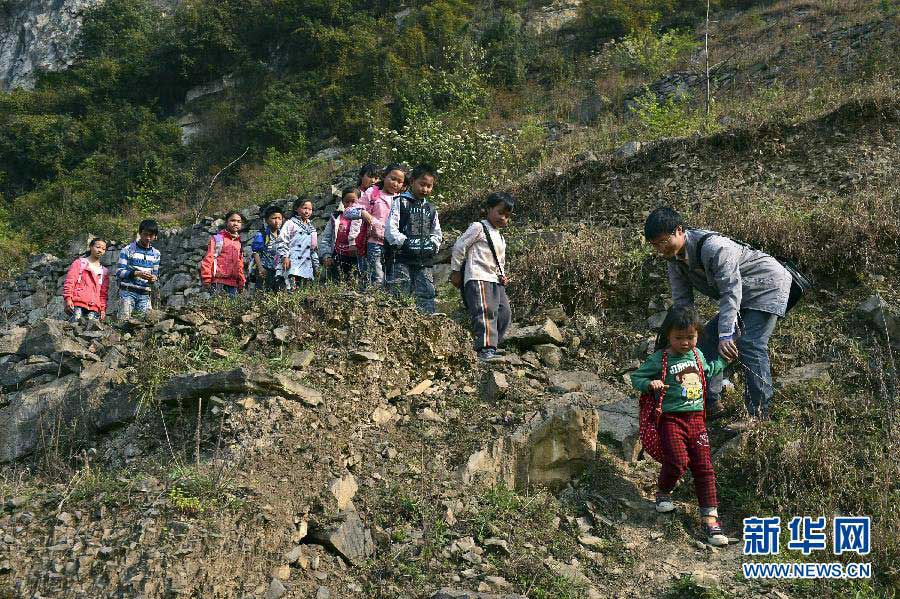 Xu Liangfan, principal of Banpo School, guides the students through the rugged path to the school on March 11, 2013. (Xinhua/Peng Nian)