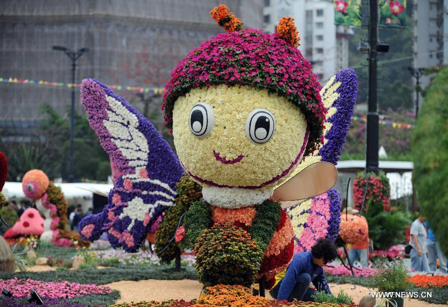 A staff member works by a parterre themed on insects displayed at a flower show in south China's Hong Kong, March 14, 2013. The 10-day Hong Kong Flower Show 2013, which will kick off on March 15, 2013 at Victoria Park, opened to media for a preview on Thursday. More than 200 organizations contributed some 350,000 flowers to the show. (Xinhua/Zhao Yusi)  