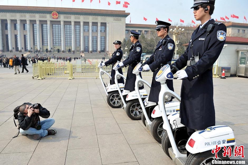A journalist sits on the ground to take photos of the policemen on duty. (Chinanews.com/ Liu Zhankun) 