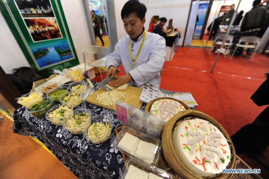 A man demonstrates folk cuisine during the 2013 China International Exhibition for Caravanning, Motoring, Tourism (CMT China) in Nanjing, capital of east China's Jiangsu Province, March 15, 2013. The three-day exhibition, with the participation of 289 exhibitors from 28 countries and regions, opened in Nanjing Friday. (Xinhua/Shen Peng) 