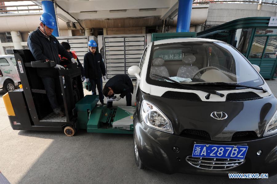 Workers install a battery panel onto an electric car at a power station in Hangzhou, capital of east China's Zhejiang Province, March 15, 2013. Hangzhou launched a rental service of electric vehicles recently, offering a three-month term with a fee of 998 Yuan per-month. (Xinhua/Ju Huanzong)