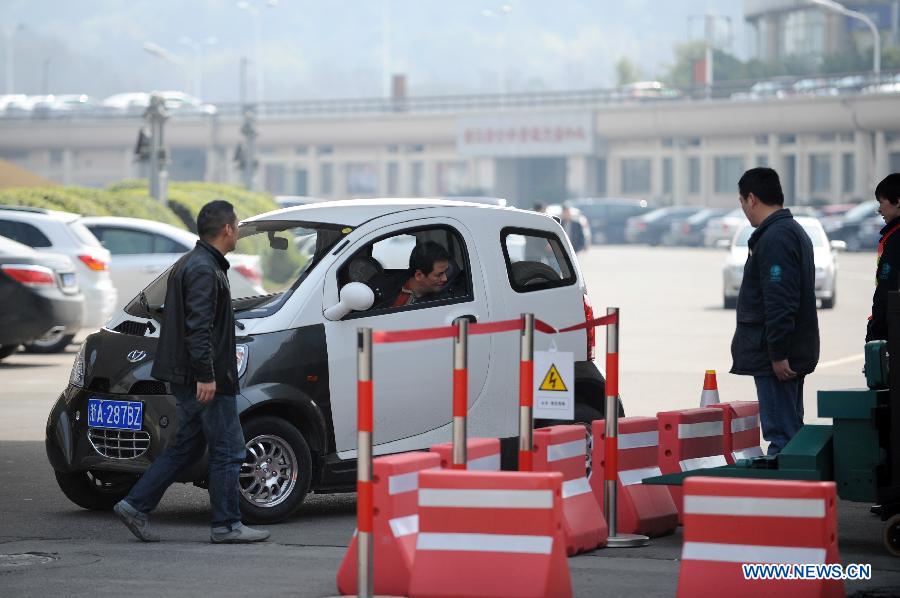 A man driving an electric car enters a power station in Hangzhou, capital of east China's Zhejiang Province, March 15, 2013. Hangzhou launched a rental service of electric vehicles recently, offering a three-month term with a fee of 998 Yuan per-month. (Xinhua/Ju Huanzong)