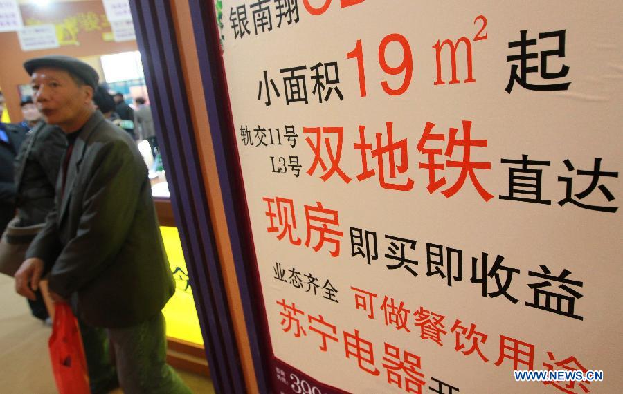 People walk past a board advertising for small spaced households along the metro lines at a real estate expo in east China's Shanghai Municipality, March 15, 2013. The expo lasts from March 15 to March 18. (Xinhua/Pei Xin)