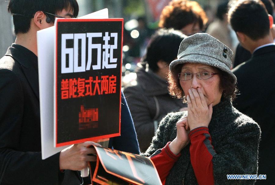 A staff member (L) of a property developer introduces their houses to a man at a real estate expo in east China's Shanghai Municipality, March 15, 2013. The expo lasts from March 15 to March 18. (Xinhua/Pei Xin)