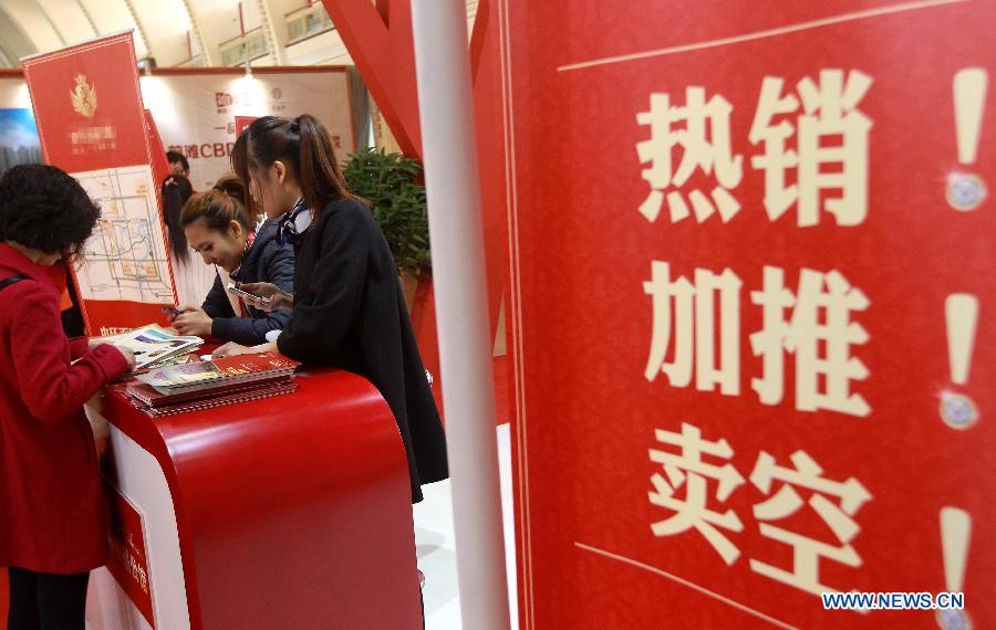 A woman communicates with staff members of a property developer at a real estate expo in east China's Shanghai Municipality, March 15, 2013. The expo lasts from March 15 to March 18. (Xinhua/Pei Xin) 