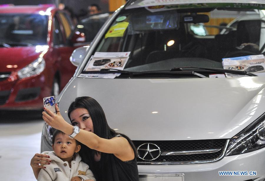 A car model takes pictures with a child during a four-day automobile show in Urumqi, capital of northwest China's Xinjiang Uygur Autonomous Region, March 16, 2013. More than 1,000 types of vehicles from over 80 automakers were displayed at the show that kicked off on Friday. (Xinhua/Jiang Wenyao) 
