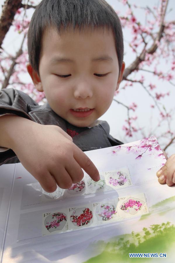 A boy presents the "peach blossom" stamps in Jinyun County, east China's Zhejiang Province, March 16, 2013. China Post published a set of "peach blossom" stamps on Saturday. (Xinhua/Xu Xiaofeng)  