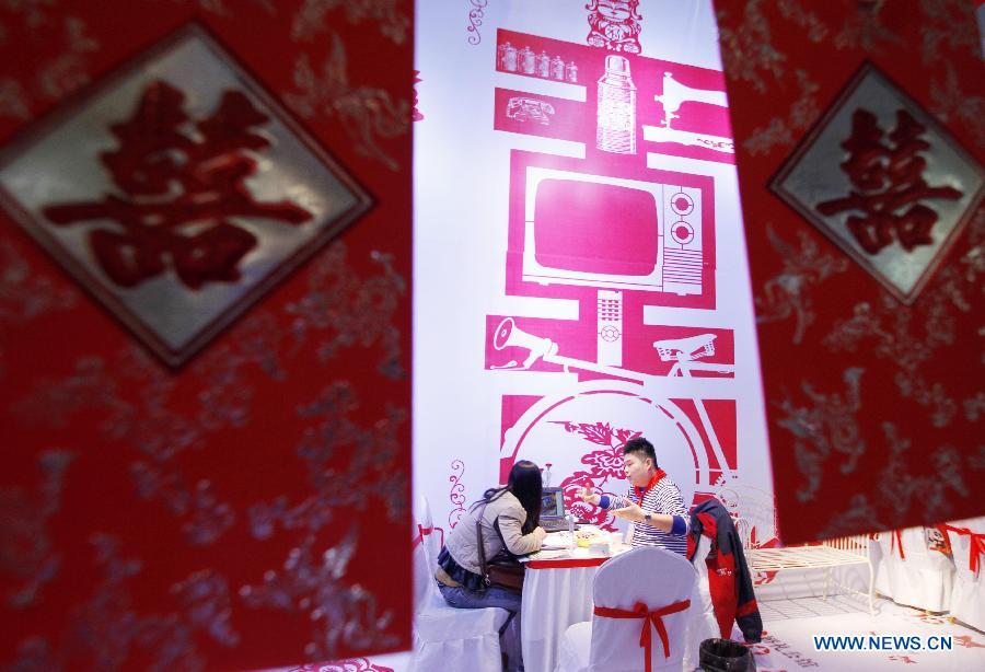 A working staff introduces wedding services to a visitor during the 2013 Xici Wedding Expo for Spring in Nanjing, capital of east China's Jiangsu Province, March 16, 2013. Most of the exhibitors possess both physical stores and online shops, attracting many net users to the expo which will last to March 17. (Xinhua/Dong Jinlin)