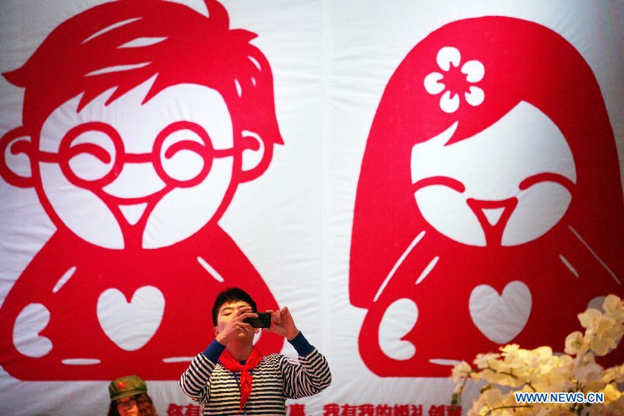 A working staff takes photo during the 2013 Xici Wedding Expo for Spring in Nanjing, capital of east China's Jiangsu Province, March 16, 2013. Most of the exhibitors possess both physical stores and online shops, attracting many net users to the expo which will last to March 17. (Xinhua) 