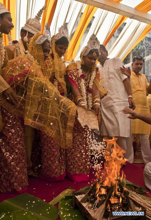 Indian brides and grooms perform rituals during a mass marriage ceremony in Calcutta, capital of eastern Indian state West Bengal, March 17, 2013. A total of 51 couples got married in this occasion on Sunday. Mass marriages in India are organized by social organizations primarily to help the economically backward families who can't afford the high ceremony costs as well as the customary dowry and expensive gifts which are still prevalent in many communities. (Xinhua/Tumpa Mondal)