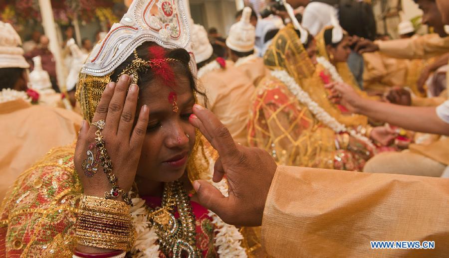 Indian brides and grooms perform rituals during a mass marriage ceremony in Calcutta, capital of eastern Indian state West Bengal, March 17, 2013. A total of 51 couples got married in this occasion on Sunday. Mass marriages in India are organized by social organizations primarily to help the economically backward families who can't afford the high ceremony costs as well as the customary dowry and expensive gifts which are still prevalent in many communities. (Xinhua/Tumpa Mondal)