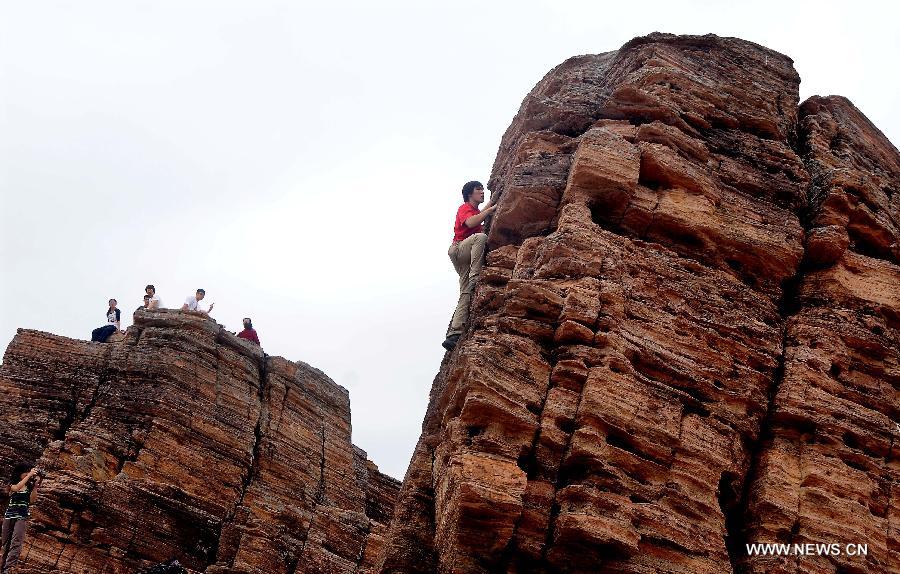 A tourist climbs up a shale rock on the Tung Ping Chau island of south China's Hong Kong, March 17, 2013. Tung Ping Chau lies in the northeast corner of Hong Kong and is part of the Hong Kong Geopark. The island is home to shale rocks in various shapes which makes it a popular tourist attraction. (Xinhua/Chen Xiaowei)