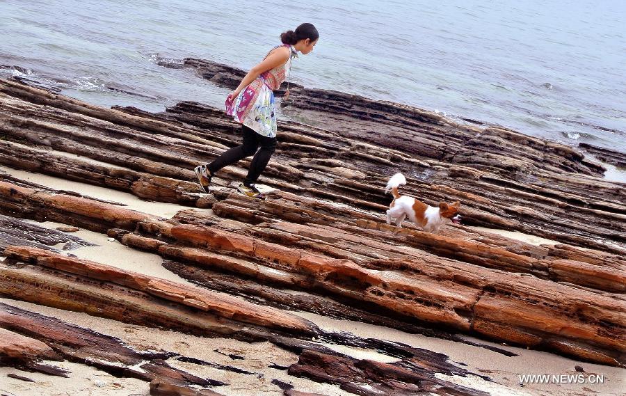 A tourist goes for a walk with her pet dog on the Tung Ping Chau island of south China's Hong Kong, March 17, 2013. Tung Ping Chau lies in the northeast corner of Hong Kong and is part of the Hong Kong Geopark. The island is home to shale rocks in various shapes which makes it a popular tourist attraction. (Xinhua/Chen Xiaowei)