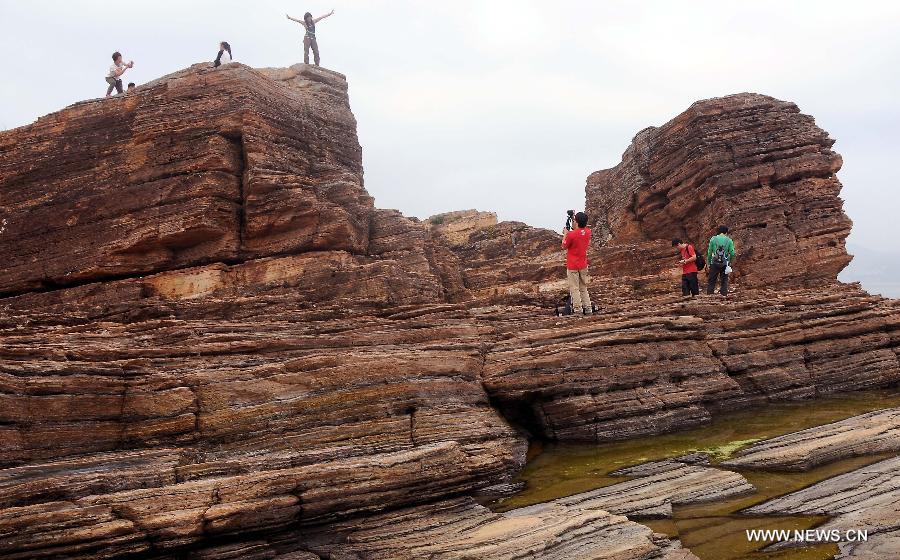 Tourists pose for photos on the Tung Ping Chau island of south China's Hong Kong, March 17, 2013. Tung Ping Chau lies in the northeast corner of Hong Kong and is part of the Hong Kong Geopark. The island is home to shale rocks in various shapes which makes it a popular tourist attraction. (Xinhua/Chen Xiaowei)