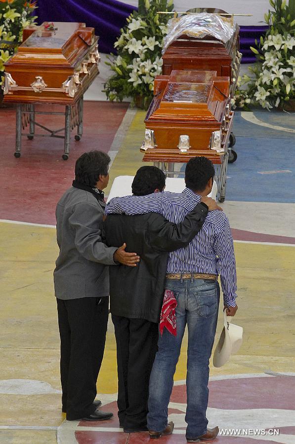 Relatives and friends stand beside the coffins of victims of a fireworks accident during a mass funeral at the village of Nativitas in Tlaxcala state, Mexico, on March 17, 2013. At least 13 people were killed and 154 others injured when a truck containing fireworks exploded during a Catholic procession in honor of a local patron saint. (Xinhua/Juan Mateo) 
