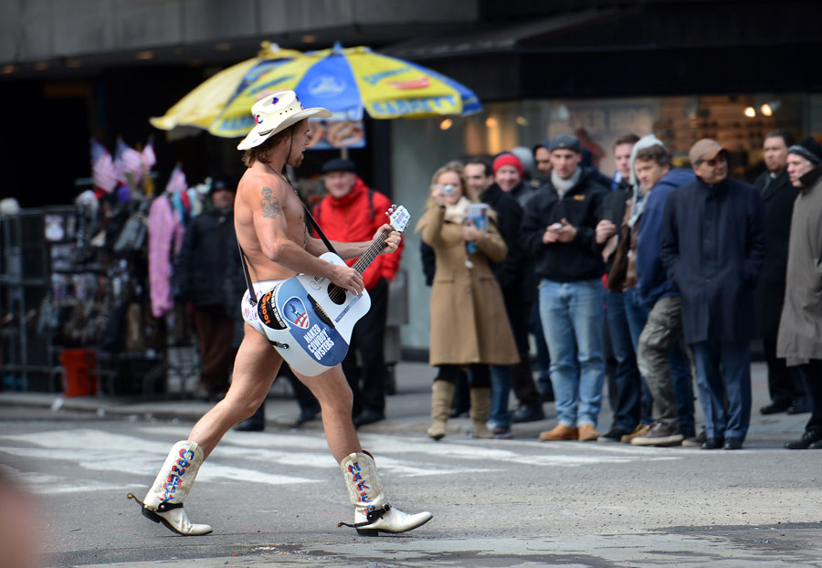 A street performer plays a guitar in only shorts and boots at the Times Square in New York, March 14, 2013. Data released on the 14th from U.S. Labor Department shows, last week, the U.S. initial claims for unemployment benefits has fallen to 332,000, lower than economists’ expected 350,000. The moving average of Initial claims for jobless benefits within four weeks decreased 2,750 to 346,750, the lowest point since March 8, 2008, which indicates the U.S. employment market is steadily improving. (/Xinhua/Wang Lei)