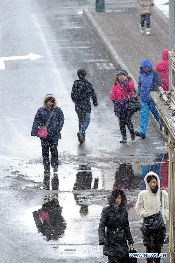 Citizens walk amid snowfall on a road in Harbin, capital of northeast China's Heilongjiang Province, March 18, 2013. A cold front brings snow and low temperature to Harbin on March 18. (Xinhua/Wang Song)  