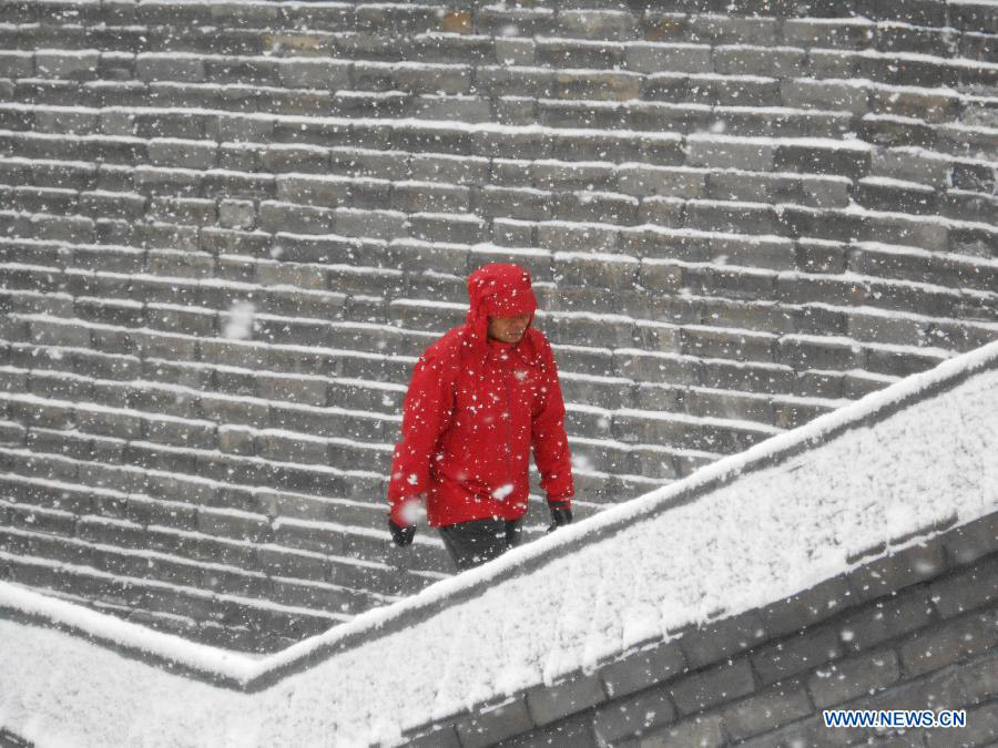 A local resident walks in snow at a river port in Jilin City, northeast China's Jilin Province, March 18, 2013. A snowfall hit the city from Sunday night. (Xinhua/Wang Mingming)