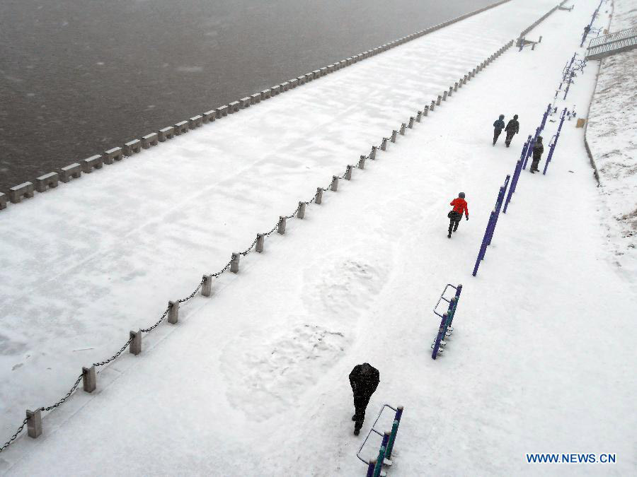 Local residents walk in snow on a street in Jilin City, northeast China's Jilin Province, March 18, 2013. A snowfall hit the city from Sunday night. (Xinhua/Wang Mingming)