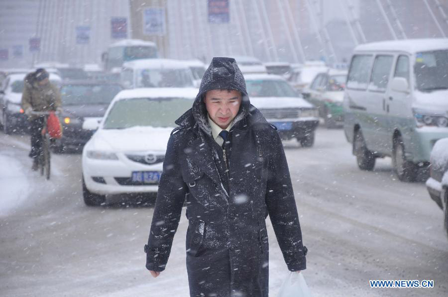 A man walks in snow on a road in Jilin City, northeast China's Jilin Province, March 18, 2013. A snowfall hit the city from Sunday night. (Xinhua/Wang Mingming)