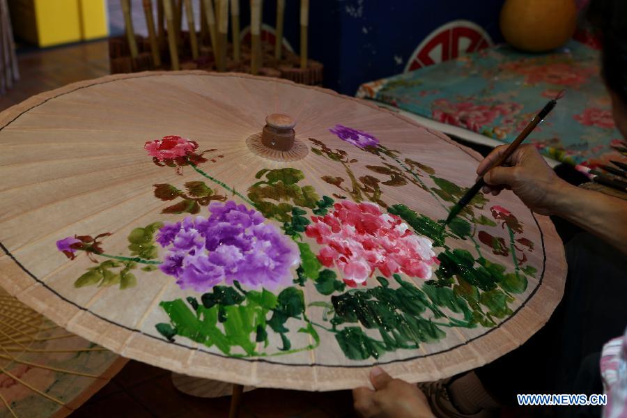 A man paints an oil paper umbrella in Yuanxiangyuan Village of Kaohsiung City in southeast China's Taiwan, March 18, 2013. The Yuanxiangyuan Village has attracted a good many tourists thanks to its burgeoning oil paper umbrella industry. (Xinhua/Xie Xiudong)