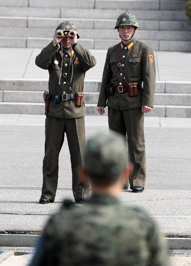 Soldiers (rear) of the Democratic People's Republic of Korea (DPRK) stands guard at the truce village of Panmunjom in the demilitarized zone (DMZ) in Paju, South Korea, March 19, 2013. The annual joint military exercises of South Korea and the United States is scheduled to run from March 11 to March 21. (Xinhua/Park Jin-hee) 